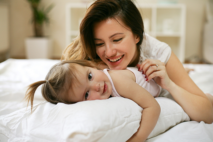 Military mother teaching toddler while lying on a bed, sharing a joyful and intimate moment at home. Military mother teaching toddler while lying on a bed, sharing a joyful and intimate moment at home.
