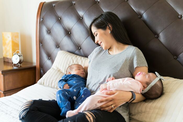 Mother sitting on bed holding two babies, illustrating bizarre and unbelievable names people actually gave their children.