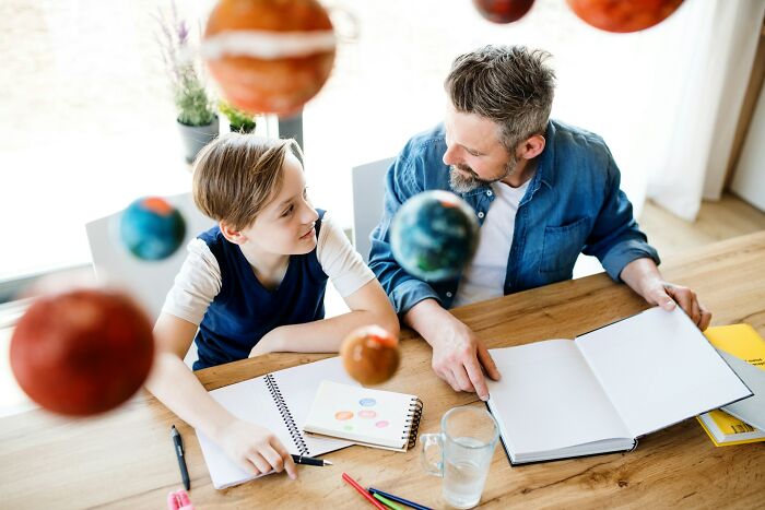 Father and son exploring educational astronomy models at home, highlighting modern parenting trends in learning activities.