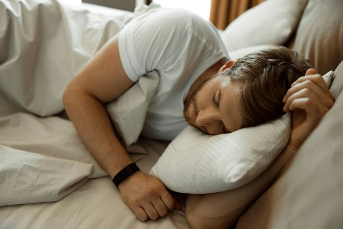 Man lying in bed asleep, illustrating harmless but toxic habits that affect daily health and well-being.