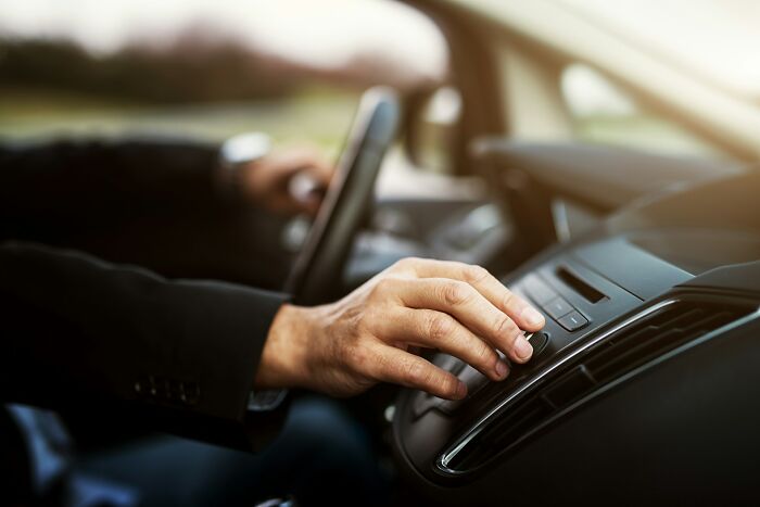 Person adjusting car controls inside vehicle, illustrating unexpected moments during funerals and related events.