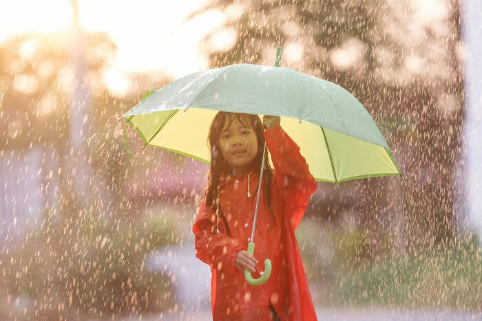 Child in a red raincoat holding an umbrella in the rain, illustrating bizarre and unusual names given to children.