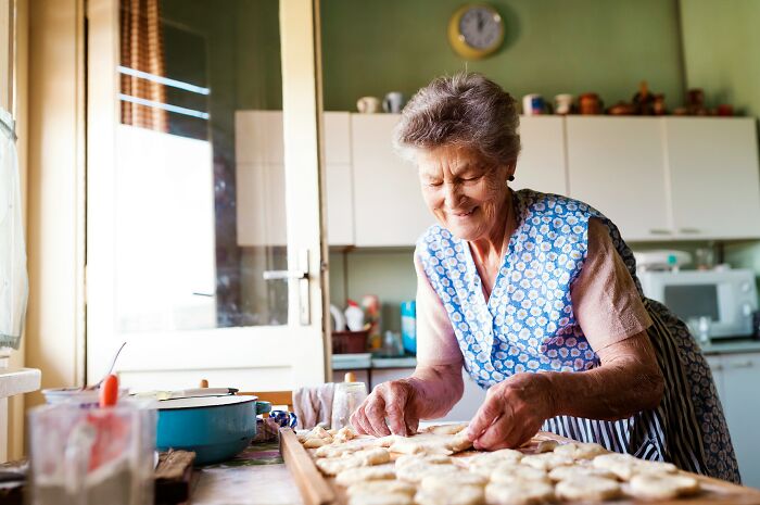 Elderly woman in a cozy kitchen preparing dough, illustrating shocking secrets people trust strangers online with.