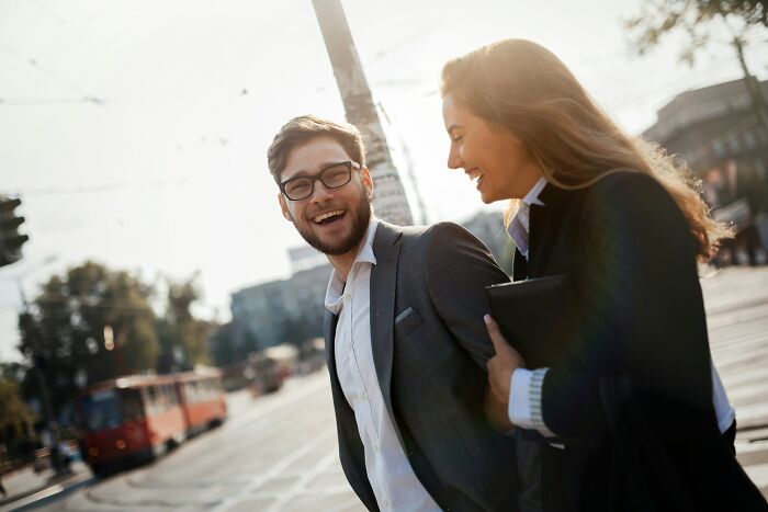 Two young professionals smiling on a city street, illustrating small decisions that changed the course of their lives.