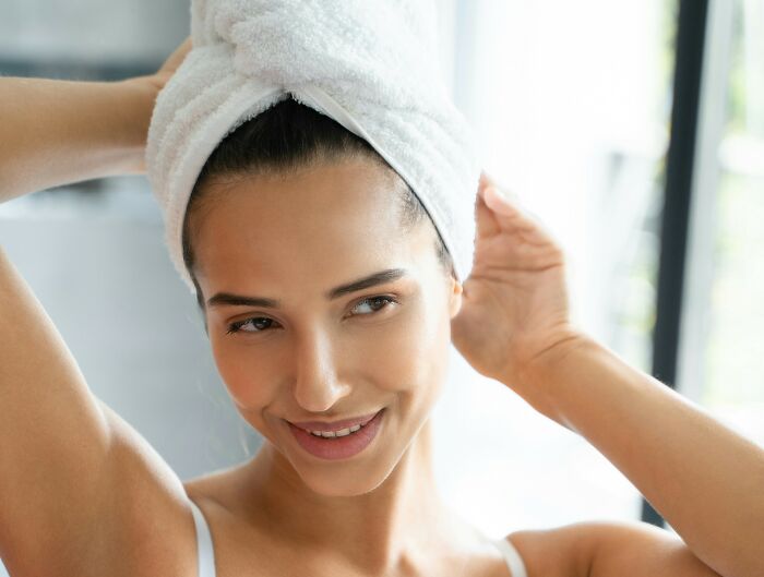 Woman with towel wrapped around her head after shower, illustrating everyday things people accidentally did wrong.