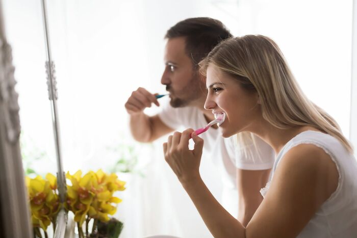 A couple brushing teeth together in the bathroom, illustrating everyday things people accidentally did wrong.
