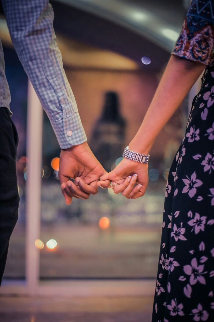 Close-up of a couple holding hands secretly, highlighting a relationship with a guy who already has a girlfriend. Close-up of a couple holding hands secretly, highlighting a relationship with a guy who already has a girlfriend.