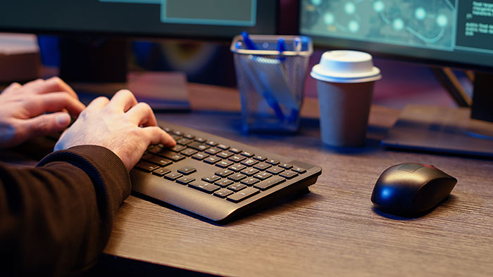 Man typing on a spare keyboard at a desk with a coffee cup and computer mouse, highlighting keyboard lending gesture. Man typing on a spare keyboard at a desk with a coffee cup and computer mouse, highlighting keyboard lending gesture.