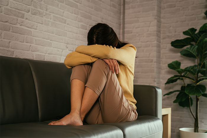 Woman sitting on couch with head buried in arms, feeling upset after unthoughtful Christmas gift from boyfriend. Woman sitting on couch with head buried in arms, feeling upset after unthoughtful Christmas gift from boyfriend.