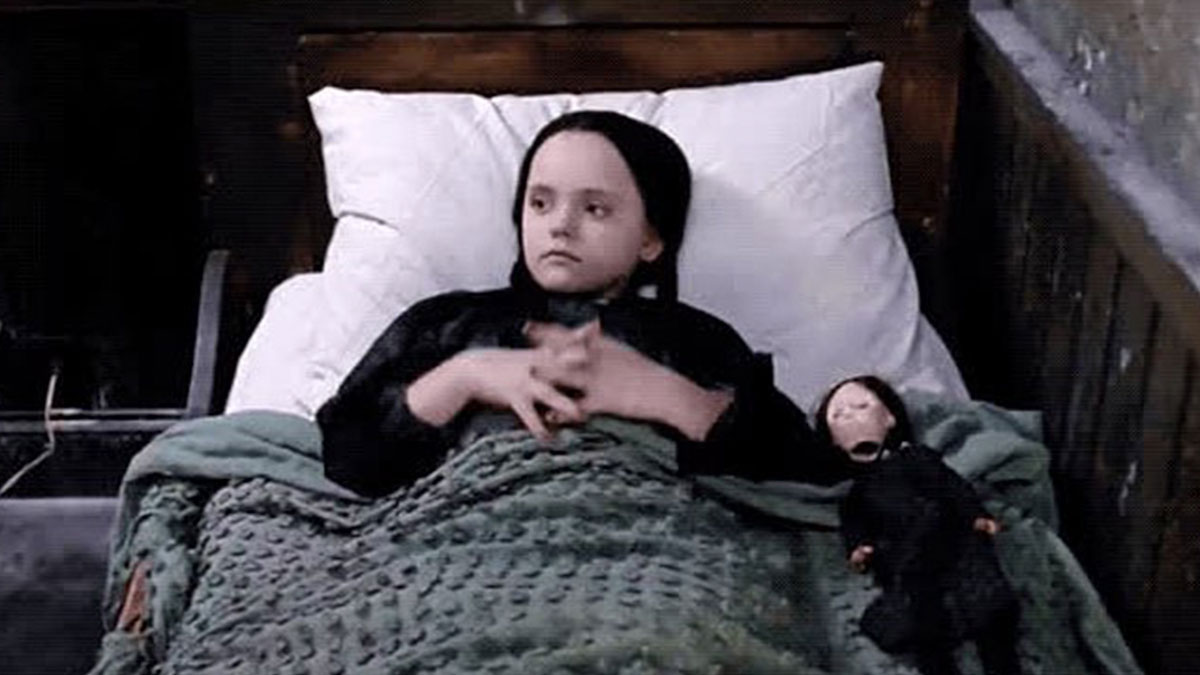 Young goth girl lying in bed with a gothic doll, reflecting goth memes for anyone who doesn't fit in.