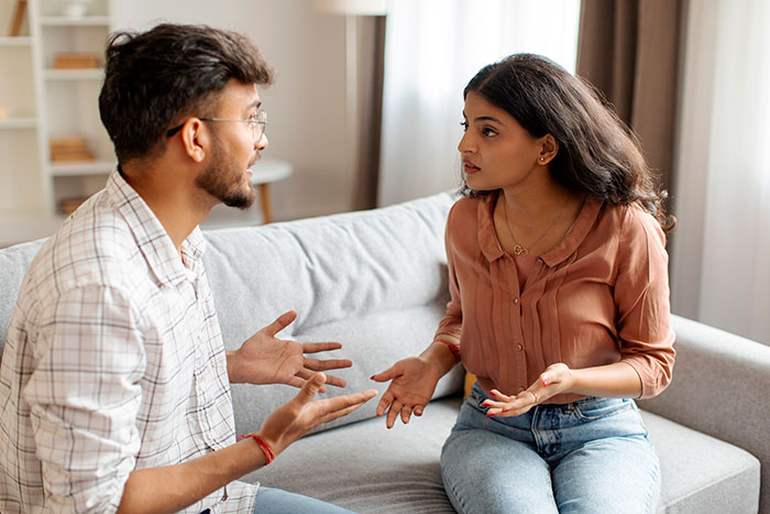 Young man and woman having a tense conversation on a couch, highlighting conflict in family relationships. Young man and woman having a tense conversation on a couch, highlighting conflict in family relationships.