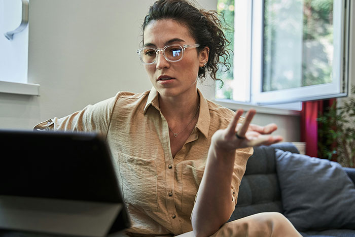 Woman in glasses speaking seriously on a digital device during a private therapy session recording concern discussion. Woman in glasses speaking seriously on a digital device during a private therapy session recording concern discussion.