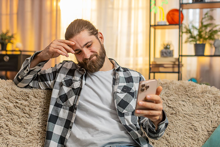 Man in a plaid shirt holding phone, appearing concerned, depicting guy recording wife’s private therapy sessions out of concern. Man in a plaid shirt holding phone, appearing concerned, depicting guy recording wife’s private therapy sessions out of concern.