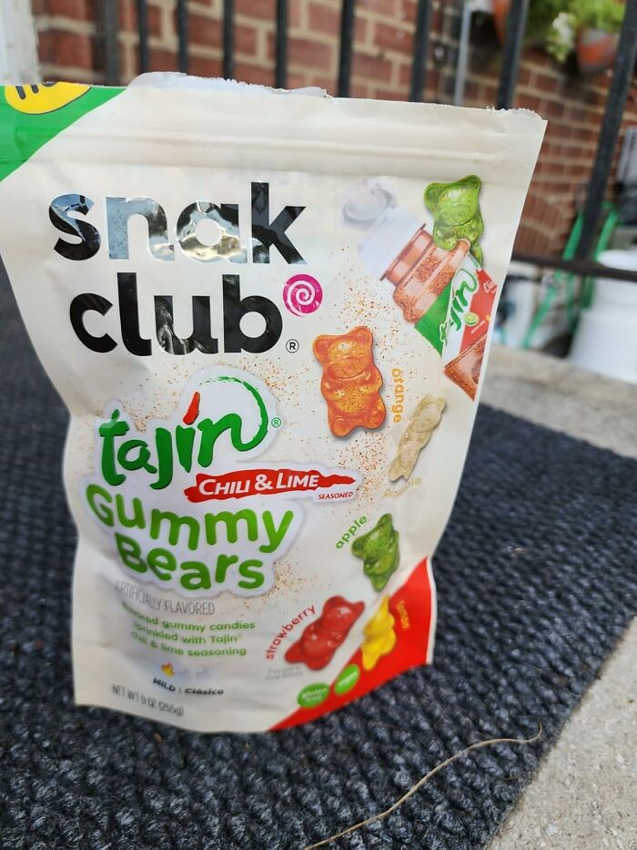 Snack club Tajin chili and lime gummy bears bag displayed outdoors on textured surface, a wacky food snack gift option.