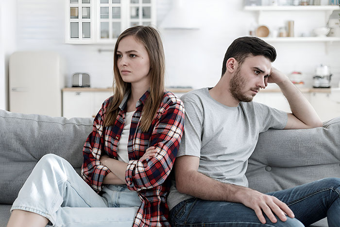 Upset couple sitting apart on couch after guy goes above and beyond for his ex girlfriend causing tension. Upset couple sitting apart on couch after guy goes above and beyond for his ex girlfriend causing tension.