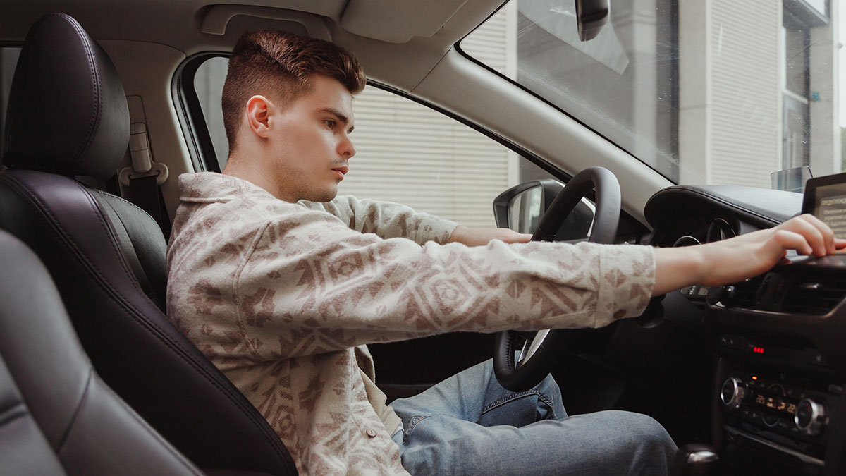 Young man sitting inside a car, adjusting the dashboard controls, related to half-brother arrest and car theft conflict.