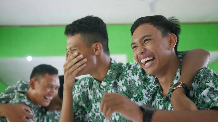 Three young men in matching patterned shirts laughing together, capturing moments of backstabbing regrets and confessions.