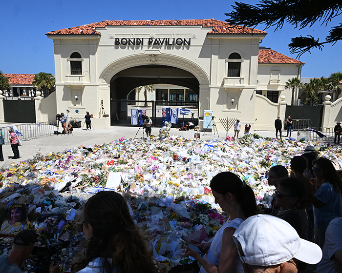 Memorial at Bondi Pavilion with crowds honoring hero cop who stopped Bondi Beach attacker with a once-in-a-lifetime move.
