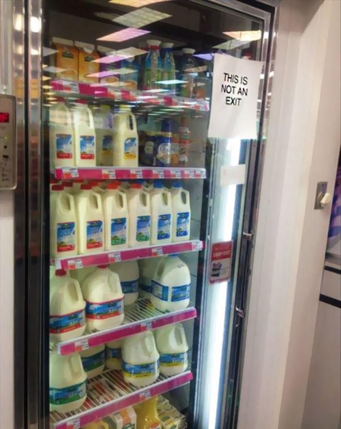 Refrigerator stocked with milk jugs and a sign humorously stating this is not an exit, reflecting funny memes for winter days.
