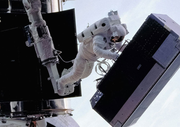 Astronaut performing a spacewalk outside a spacecraft, illustrating bizarre facts from history in space exploration.