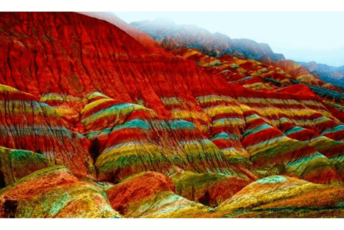 Colorful layered rock formations in a real place from around the world that look AI generated but are natural.