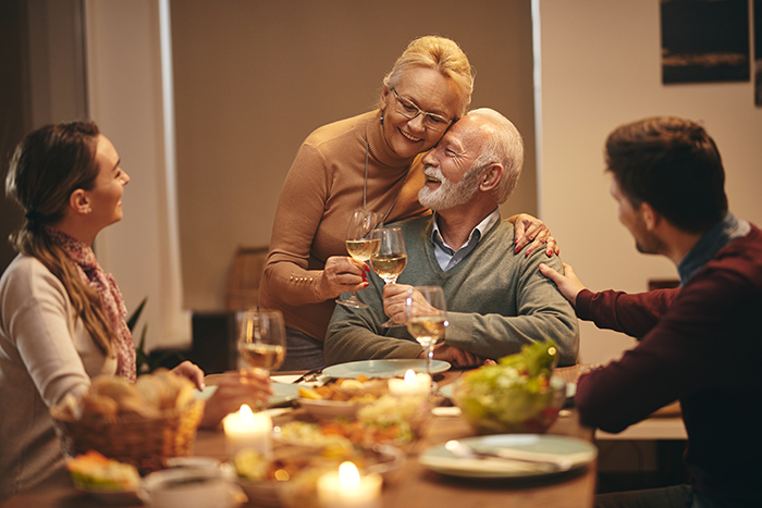 Elderly couple sharing a loving moment during dinner while family members look on, reflecting shock and lost feelings. Elderly couple sharing a loving moment during dinner while family members look on, reflecting shock and lost feelings.