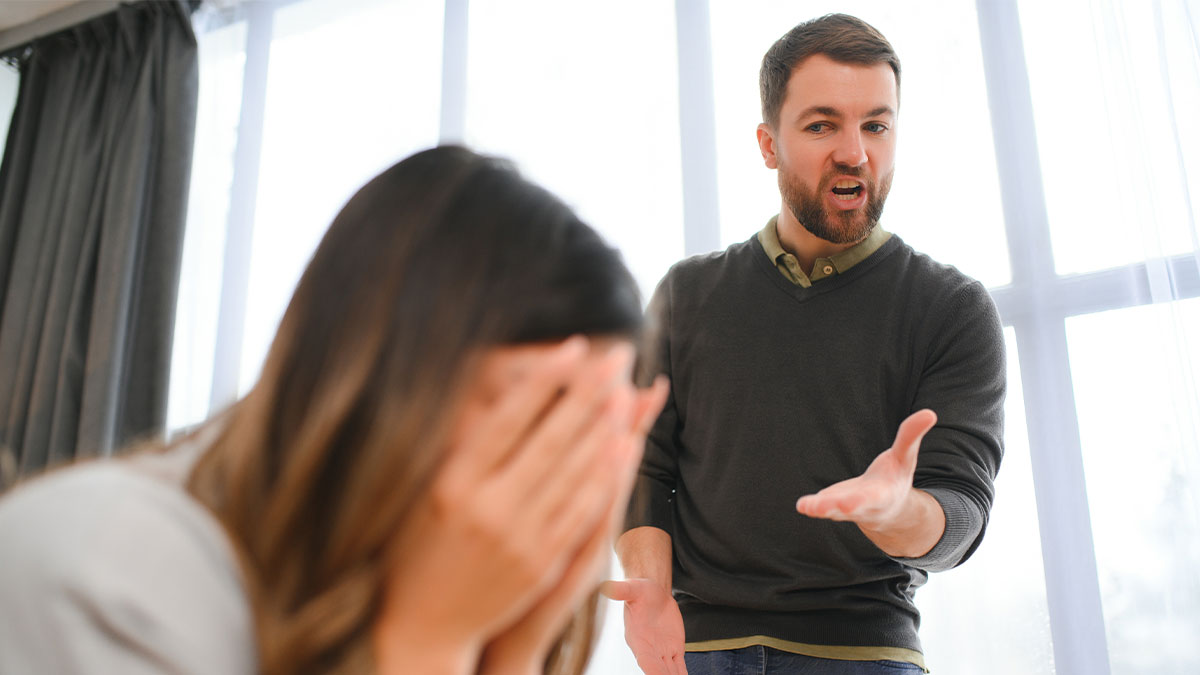 Angry man arguing with wife who covers her face, highlighting marriage falling apart over money issues.
