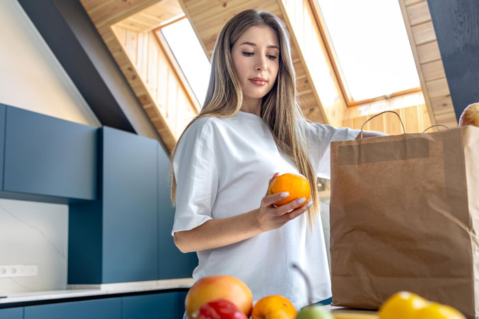 Stay-at-home-mom unpacking groceries in a modern kitchen, managing chores and parenting responsibilities.