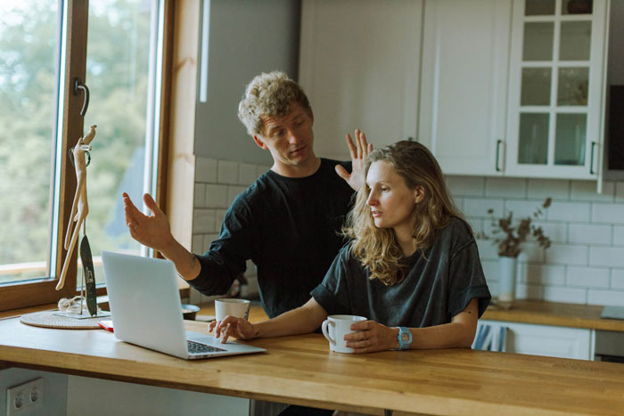 Man and woman in kitchen discussing open marriage, man appearing frustrated and unsure while woman listens quietly.