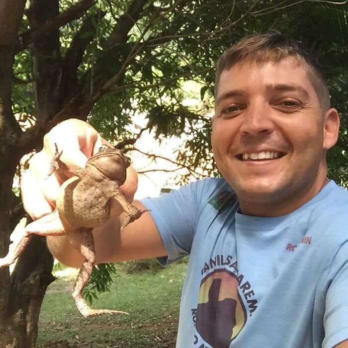 Man smiling outdoors holding a toad, unrelated to wild vulture bonding with a human or dog with wings theme. Man smiling outdoors holding a toad, unrelated to wild vulture bonding with a human or dog with wings theme.