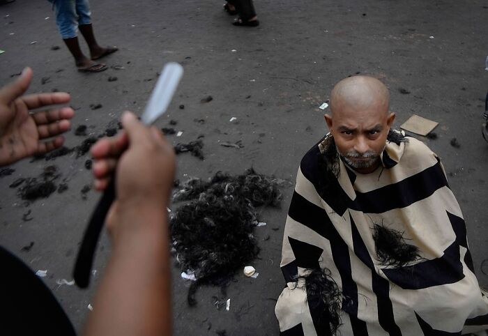 Man getting a street shave with a straight razor on a busy Mumbai road, capturing everyday life in Mumbai.