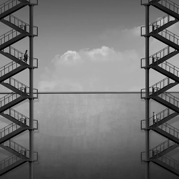 Two people on opposite staircases connected by a bridge, showcasing striking minimalism photography art in black and white.