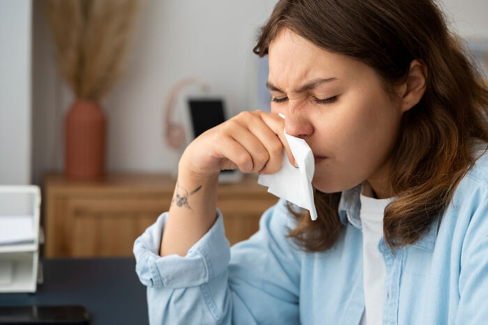 Young woman with a tissue wiping her nose, illustrating fascinating human body features and facts about health.