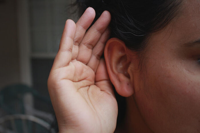 Close-up of a person holding hand to ear, highlighting fascinating human body features and facts about hearing.