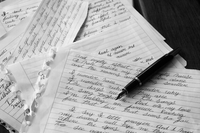 Handwritten letters and a pen on a table symbolizing hidden truths and dark secrets revealed through writing.