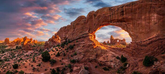 Natural red rock arch formations at sunset, one of the places that look AI generated but are actually real.