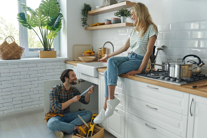 Woman refuses to be third wheel in marriage, discussing with husband while he fixes kitchen plumbing together