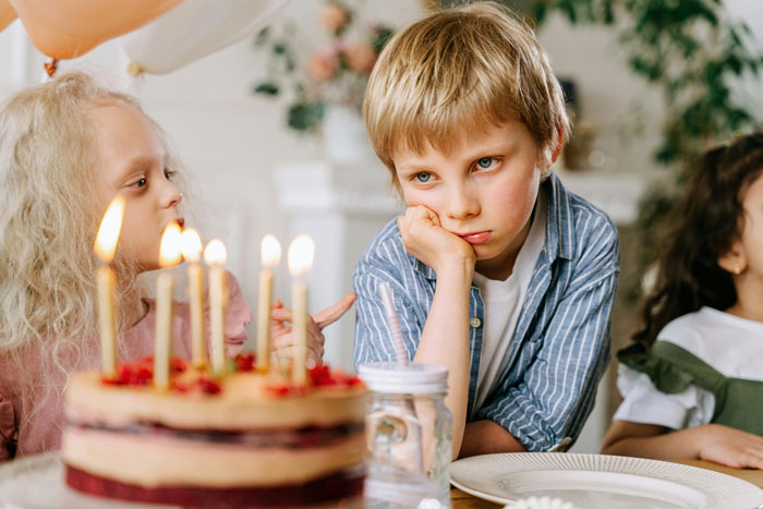 Child looking upset at birthday party with cake and candles, highlighting Jehovah's Witness mom celebration tension.