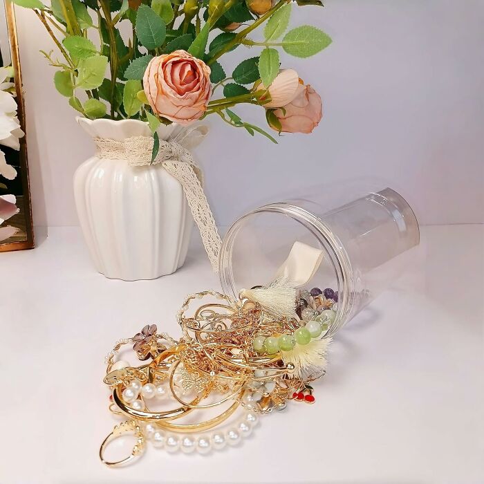 Assorted jewelry spilling from a clear blind box beside a floral vase, showcasing the excitement of blind boxes Christmas gifts.