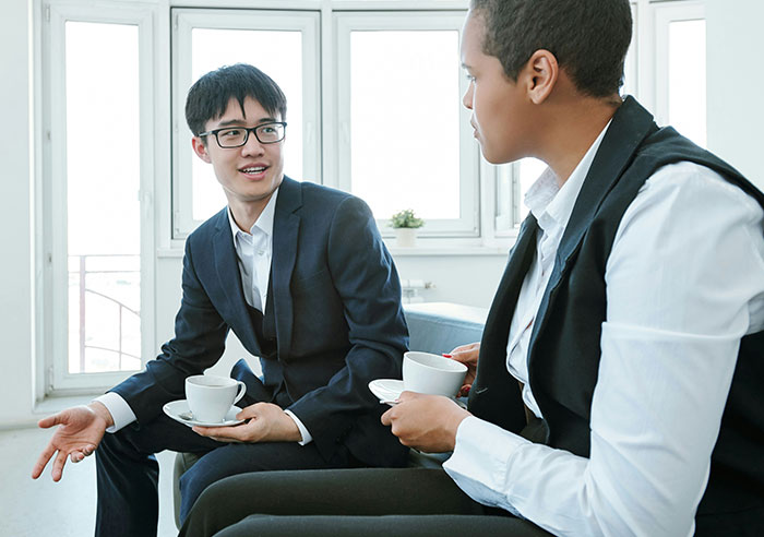 Two professionals having a coffee meeting, discussing mental questions job candidates ask recruiters in a modern office.