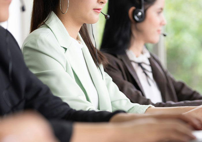 Three recruiters wearing headsets, working in a bright office, focused on job candidate mental questions during calls.