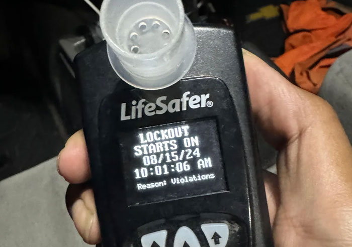 Hand holding LifeSafer device showing lockout start date and time due to violations, illustrating mental questions in job interviews.