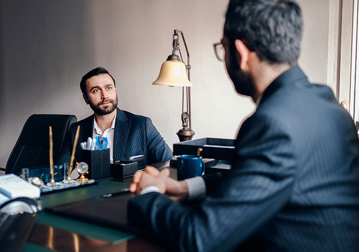 Two men in suits during a job interview, illustrating job candidates asking mental questions to recruiters.