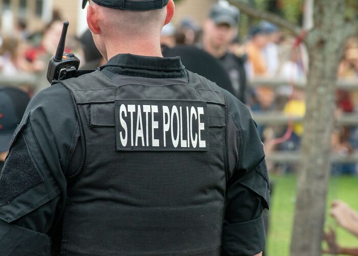 State police officer in uniform at a public event, illustrating examples of instant karma in real-life situations.