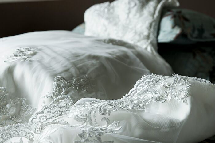 Close-up of a white wedding dress with detailed lace embroidery, symbolizing a wedding cancellation dilemma. Close-up of a white wedding dress with detailed lace embroidery, symbolizing a wedding cancellation dilemma.