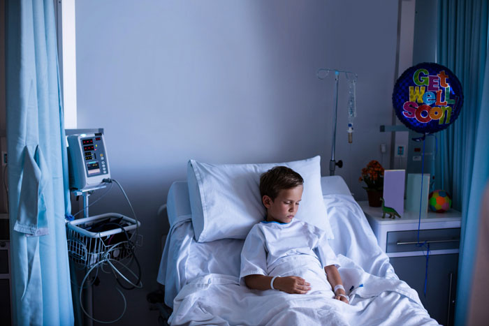 Young boy lying in hospital bed with medical equipment nearby, highlighting themes of sacrifice and spare parts concept. Young boy lying in hospital bed with medical equipment nearby, highlighting themes of sacrifice and spare parts concept.