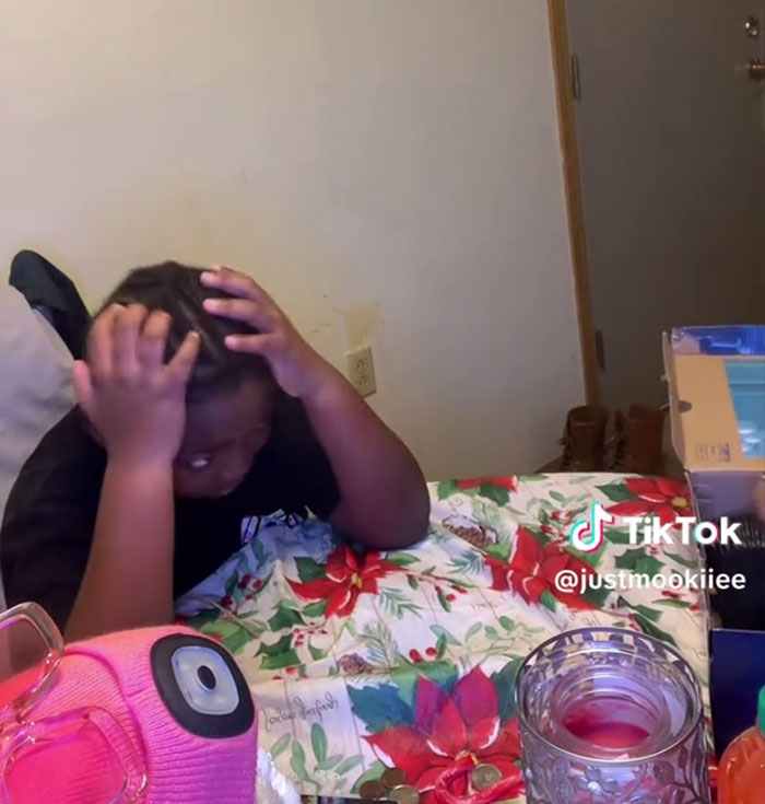 Child reacting to Angel Tree gifts on holiday-themed table as mom films for viral TikTok video about ungratefulness.