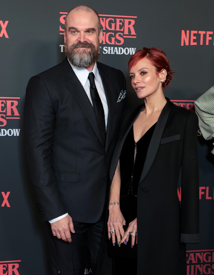 Lily Allen attending a red carpet event in a black coat and velvet dress, embracing a bearded man in a black suit. Lily Allen attending a red carpet event in a black coat and velvet dress, embracing a bearded man in a black suit.