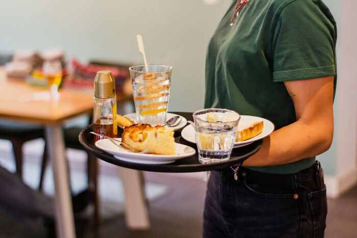 Person carrying a tray with cake slices and glasses of water, illustrating examples of instant karma in everyday moments.