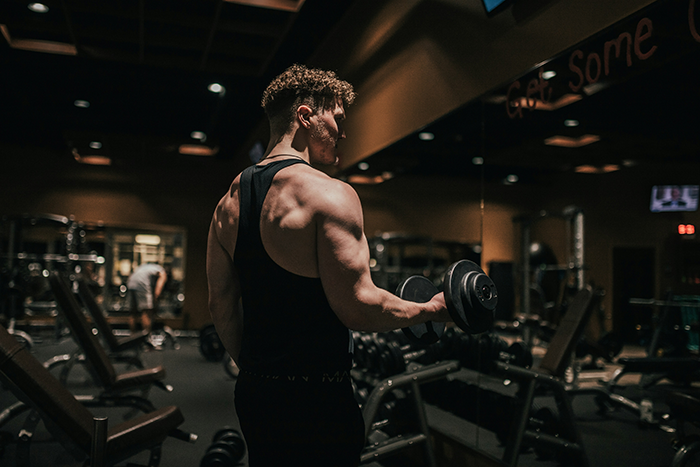 Muscular guy working out in a gym, showcasing strength and hunger for fitness in a dimly lit setting. Muscular guy working out in a gym, showcasing strength and hunger for fitness in a dimly lit setting.